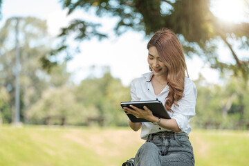 Student girl working with a digital tablet in a green park