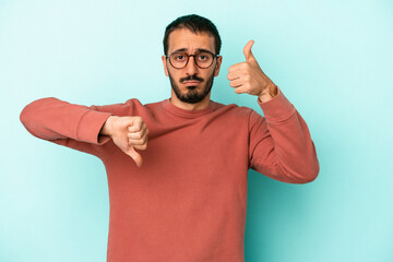 Young caucasian man isolated on blue background showing thumbs up and thumbs down, difficult choose...