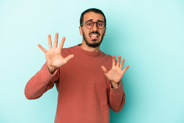 Young caucasian man isolated on blue background being shocked due to an imminent danger