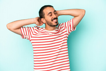 Young caucasian man isolated on blue background feeling confident, with hands behind the head.