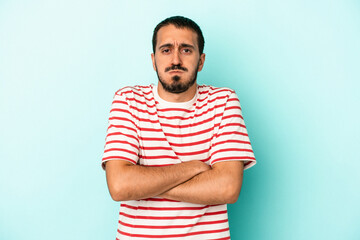 Young caucasian man isolated on blue background blows cheeks, has tired expression. Facial expression concept.