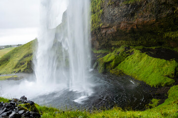 beautiful view of an Icelandic water fall during a cloudy day. The Skogafoss waterfall is a tourist attraction that brings in many visitors 