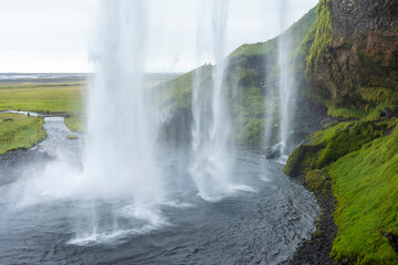 Obraz premium beautiful view of an Icelandic water fall during a cloudy day. The Skogafoss waterfall is a tourist attraction that brings in many visitors 