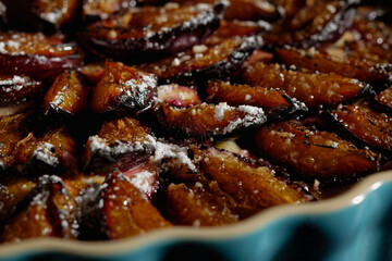 Plum cake in a tart pan, dusted with powdered sugar. Close-up.