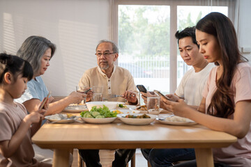 Asian Addicted family use mobile phone while eating breakfast on table. 