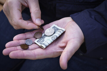 Man counting on the palm of the united states dollar banknote and small coins