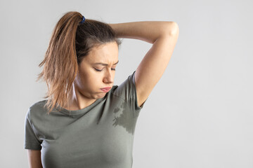 Young woman with her arm raised with her armpits sweat - obrazy, fototapety, plakaty