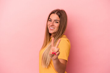 Young Russian woman isolated on pink background smiles, pointing fingers at mouth.