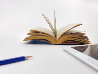 open old book on white background blur pencil and IPad It is a symbol between technology and old fashioned.