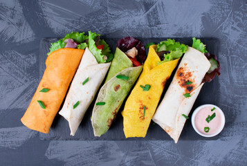 Assorted wraps with tortillas of various colors with chicken, vegetables, mushrooms, herbs and...