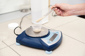 A chemist weighs a powder on an electronic scale in a biological laboratory setting.
