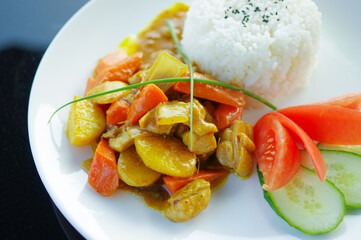 chicken curry with chopped carrot potatoes and black sesame on rice in white plate top view