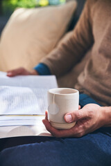 Enjoying tea time reading a book while holding tea cup