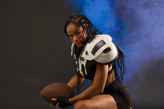 Woman With American Football Shoulder Pads, Ball And Braids