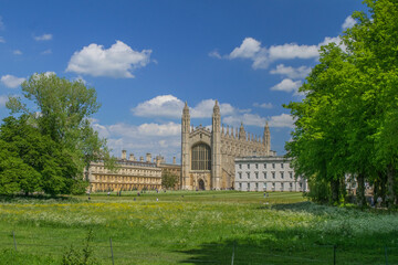 Facade of Gothic style King's College Chapel next to the Gibbs' Building among fields and trees in the University of Cambridge England