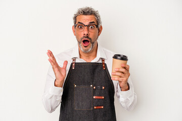 Middle age store clerk holding a take away coffee isolated on white background  surprised and...