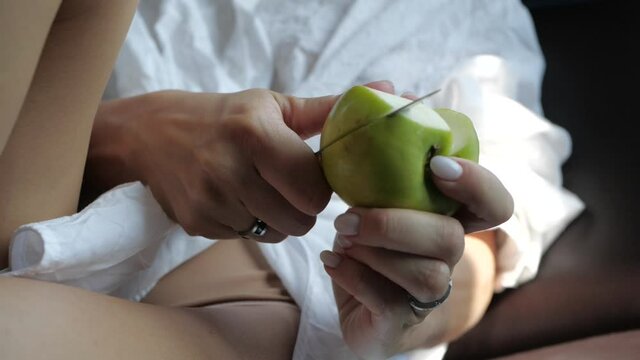 the girl sexually cuts an apple with a knife, lying in a white shirt and with bare legs. High quality FullHD footage