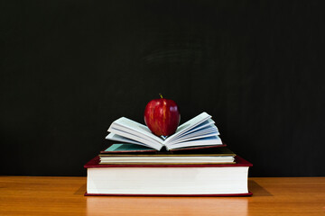 an apple placed in an open book on a wooden table