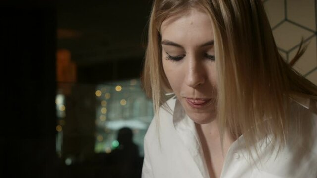 beautiful blonde girl eats deliciously sitting in a restaurant against the background of a beige wall. Video for advertising restaurant, cafe. High quality FullHD footage