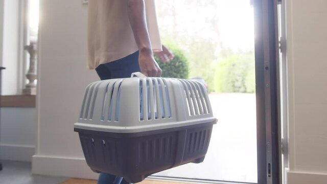 Slow motion of woman carrying pet carrier in house