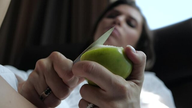 a young woman with beautiful eyes cuts off a green apple and eats it sexually. High quality FullHD footage