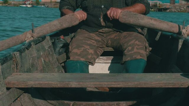 Old fisherman is towing in a dinghy boat.