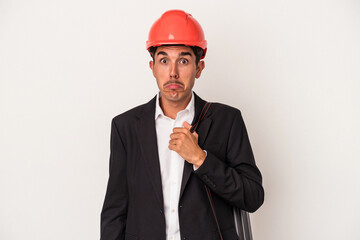 Young architect mixed race man isolated on white background shrugs shoulders and open eyes confused.