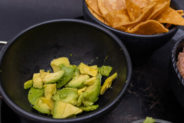 Bowls of tortilla chips and chopped avocado on Mexican comal