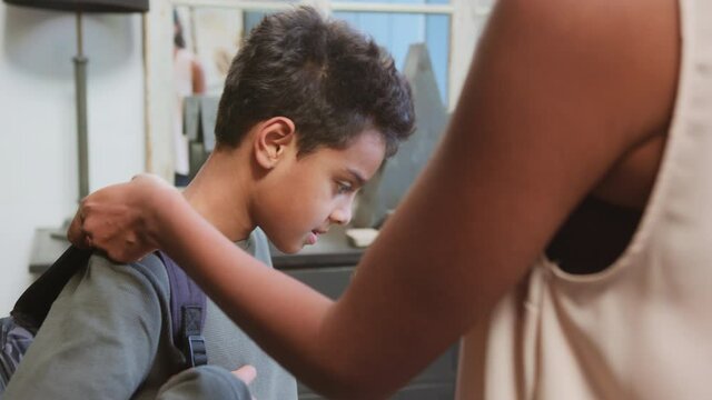 Slow motion of mother helping son with school backpack