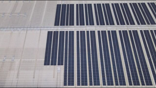 Aerial drone image of solar panels installed on a roof of a large industrial building or a warehouse. Industrial buildings.The renevable energy sustainable sources green power photovoltaic.