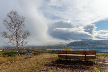 Bench overlooking the mountains and snow storm