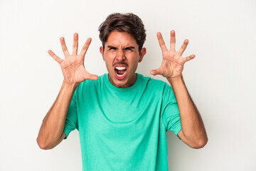 Young mixed race man isolated on white background showing claws imitating a cat, aggressive gesture.