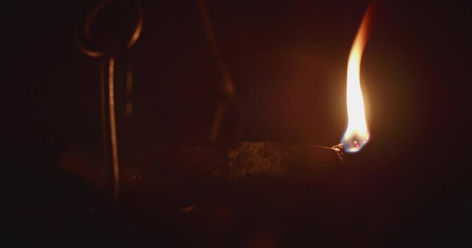 Hanged ancient rushlight burning in darkness.