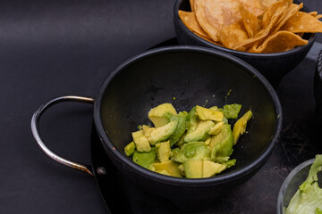 Bowls of tortilla chips and chopped avocado on Mexican comal