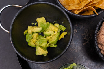 Bowls of tortilla chips and chopped avocado on Mexican comal