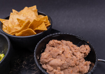 Bowls of tortilla chips and refried beans on Mexican comal