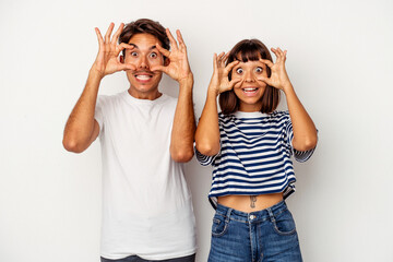 Young mixed race couple isolated on white background keeping eyes opened to find a success opportunity.