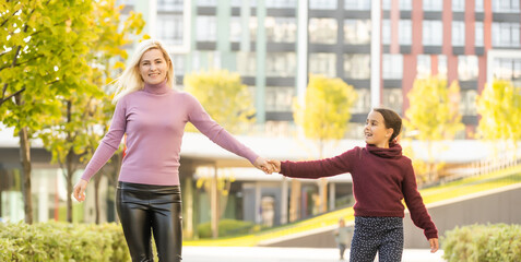 Little girl and her mother enjoy sunny weather in the autumn park