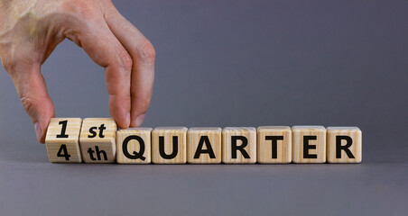 From 4th to 1st quater symbol. Businessman turns cubes and changes words '4th quater' to '1st quater'. Beautiful grey table, grey background. Business, happy 1st quater concept, copy space.