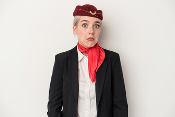 Young air hostess caucasian woman isolated on white background shrugs shoulders and open eyes...