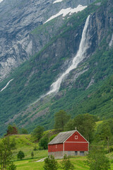 Red farm house below the mountain and waterfall.