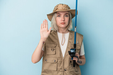 Young caucasian fisherwoman holding a rod isolated on blue background standing with outstretched hand showing stop sign, preventing you.