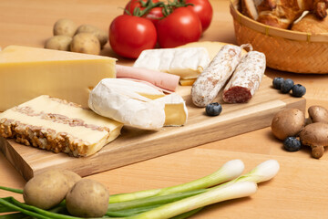 Tisch mit Holz und Käse Holzplatte, mit frischem Brot, Tomaten und Kartoffeln. Traditionelle Brotzeit für gesunde Ernährung. 