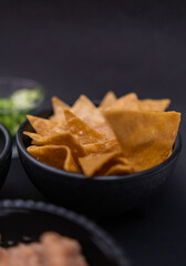 Bowls of tortilla chips and refried beans with black background