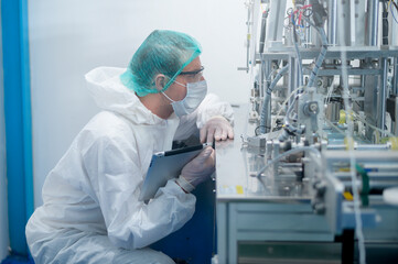 Naklejka premium Workers producing surgical mask in modern factory, Covid-19 protection and medical concept.