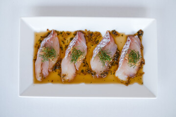 Sea bass sashimi with the sauce on white plate on white background. Isolated on white. Japanese restaurant. Japanese traditional food. Raw fish.
