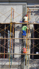 Ponorogo, Indonesia - 10 04 2021: the construction workers work together in various heights without using any safety kit.