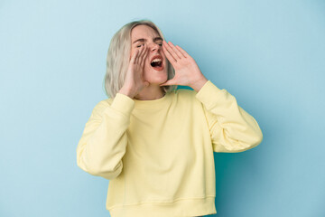 Young caucasian woman isolated on blue background shouting excited to front.