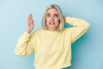 Young caucasian woman isolated on blue background screaming with rage.