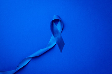Cancer awareness blue. Awareness of men health in November with blue prostate cancer ribbon isolated on deep blue background. November and International Mens Day.